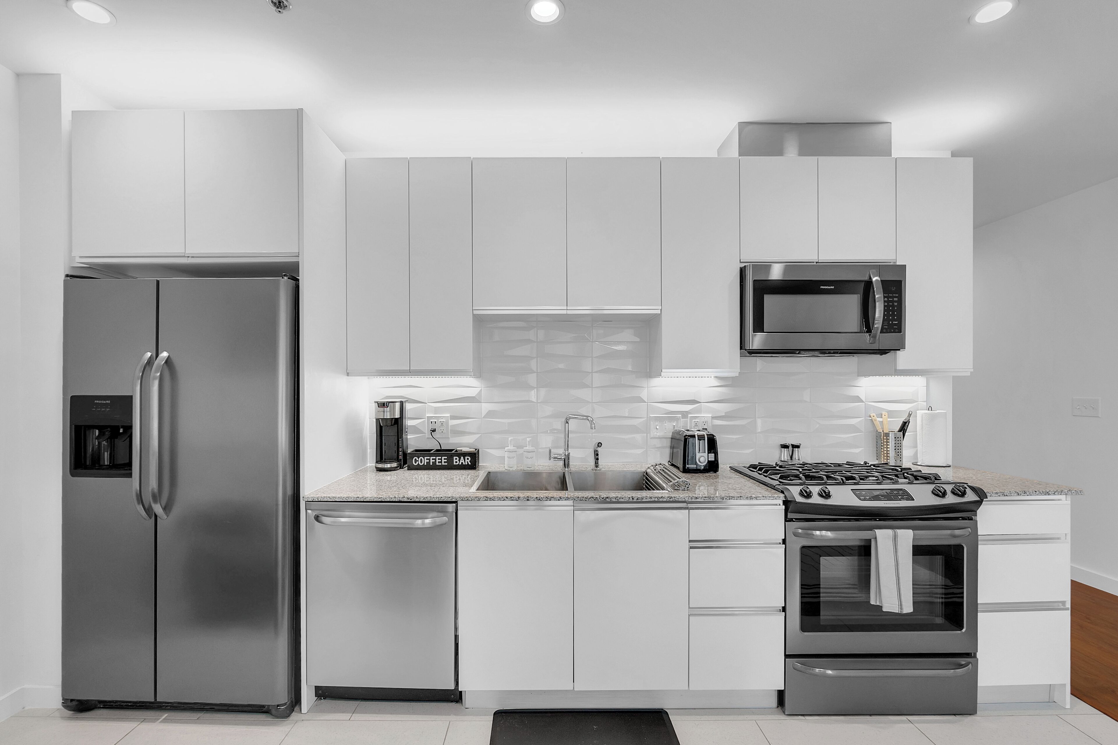 A modern kitchen with stainless steel appliances, white cabinetry, and a built-in microwave.