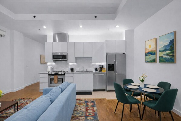 A modern kitchen with white cabinets, stainless steel appliances, and a dining area with a table and chairs.