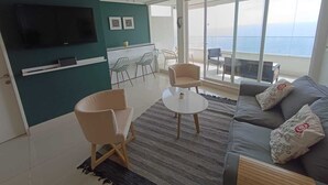 A modern living room with a sofa, chairs, a TV, a dining area, and a balcony with a view. - Apartment in Concon, in front of the sea. Wonderful view. 5 people, very complete. (Concón)