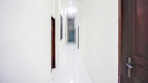 A narrow hallway with white walls and a tiled floor, leading to a door at the end. - Luxury Deluxe Double Retreat with Free WiFi (Banda Aceh)