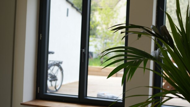 Een kamer met uitzicht op een fiets en een wit gebouw.