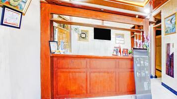 A reception desk with a wooden counter, framed certificates, and a digital screen.