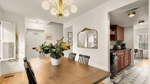 A dining area with a wooden table, chairs, a potted plant, and a chandelier. - Your Old Town Home Away From Home (Alexandria)