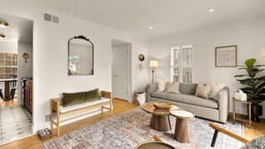 A living room with a sofa, a coffee table, a rug, and a mirror on the wall. - Your Old Town Home Away From Home (Alexandria)