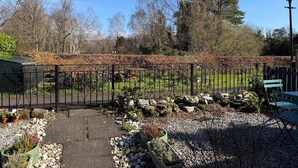 A garden with a metal fence, potted plants, and a bench. - Faerie Cottage, Luss, Loch Lomond (Luss)
