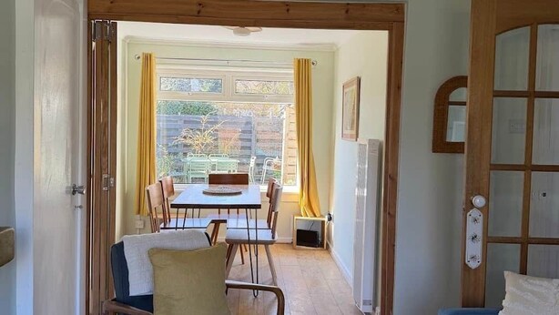 A room with a wooden dining table, a blue sofa, and a wooden ceiling fan. - Faerie Cottage, Luss, Loch Lomond (Luss)