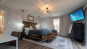 Una habitación de hotel con cama, escritorio, televisión y un ventanal grande.