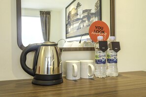 Ein Hotelzimmer mit Wasserkocher, zwei weißen Tassen, zwei Wasserflaschen und einem Schild mit der Aufschrift 'YOU look amazing'.