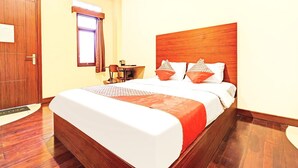 Habitación de hotel con cama de madera, mesita de noche, escritorio y ventana con cortinas.