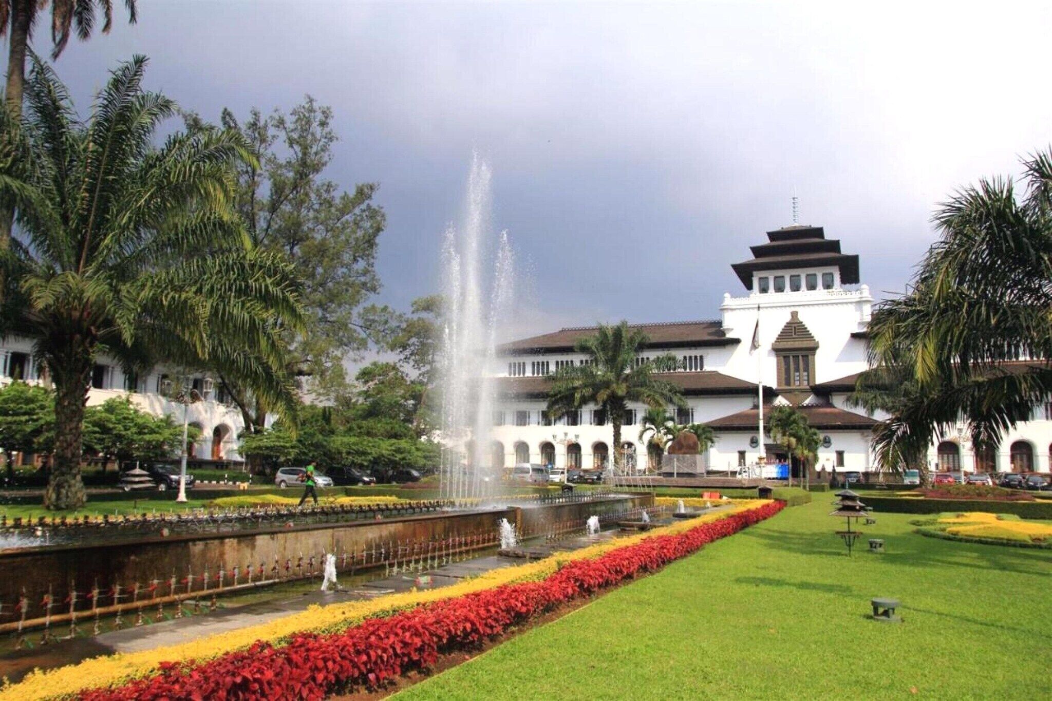 A building with a fountain, palm trees, and a well-maintained garden.