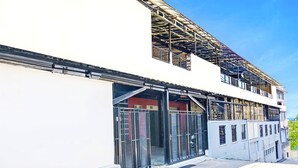 Ein mehrgeschossiges Gebäude mit modernem architektonischen Design, das große Fenster und ein Metallgerüst aufweist.