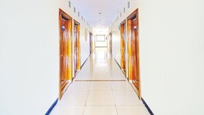 Ein langer, schmaler Hotelkorridor mit Holztüren an beiden Seiten, der zu einem hellen Raum am Ende führt.