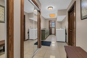 A hallway with a washing machine, a dryer, and a small table.