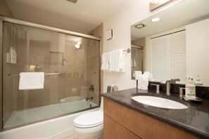A modern bathroom with a glass-enclosed shower, a white toilet, a vanity with a sink, and a mirror. - Luxe 3BR in Village, Hot Tub, Pool, Sauna, Parking (Vail)