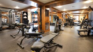 Una palestra con diverse attrezzature per l'allenamento, tra cui macchinari per pesi, tapis roulant e pesi liberi.