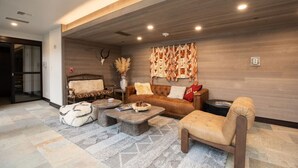 Un soggiorno moderno con divano, poltrone, tavolino e un elemento decorativo a parete.