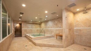 Una stanza spa con vasca idromassaggio, una panca e una zona doccia.