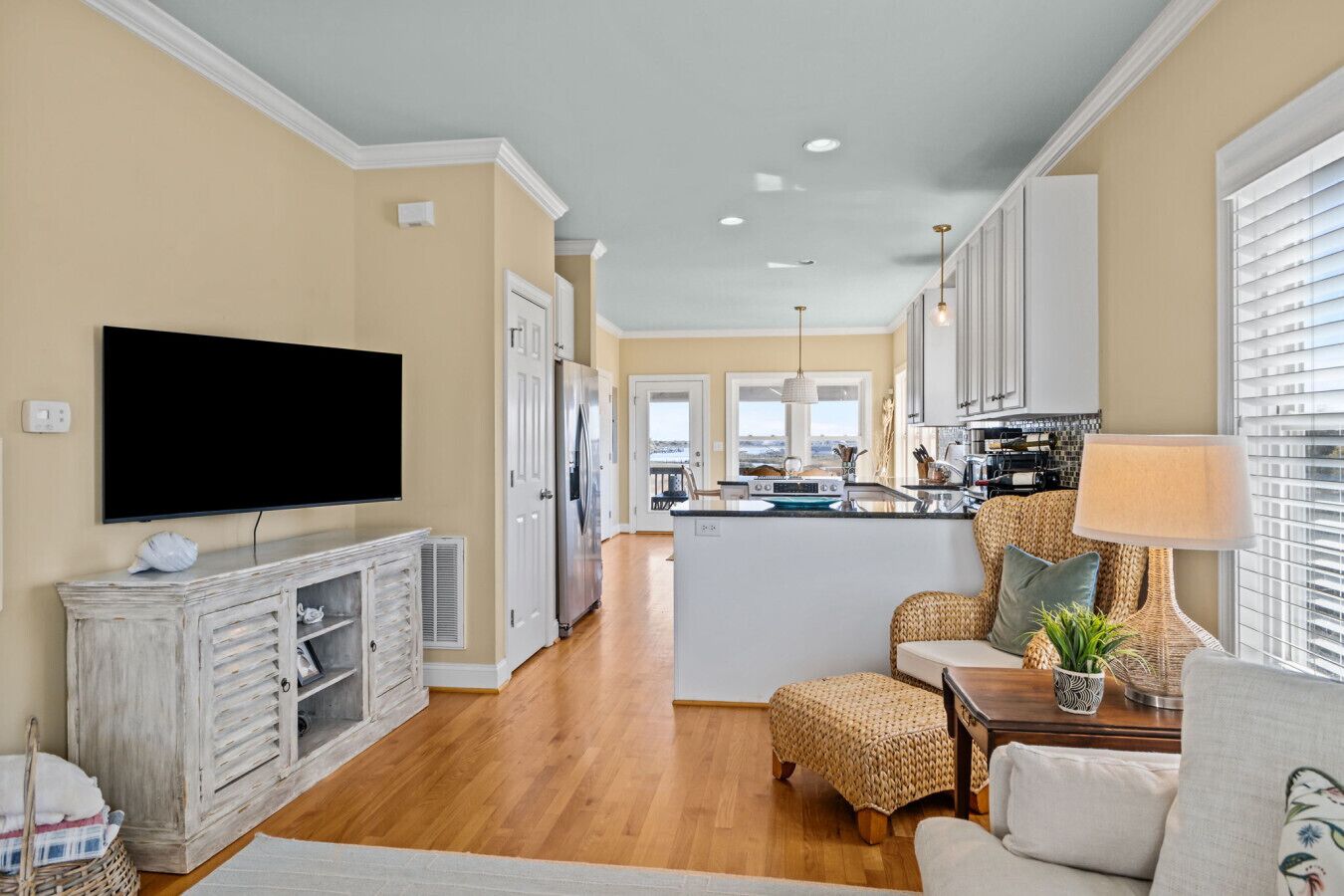 A modern kitchen with a flat-screen TV, a central island, and a dining area with wicker furniture.