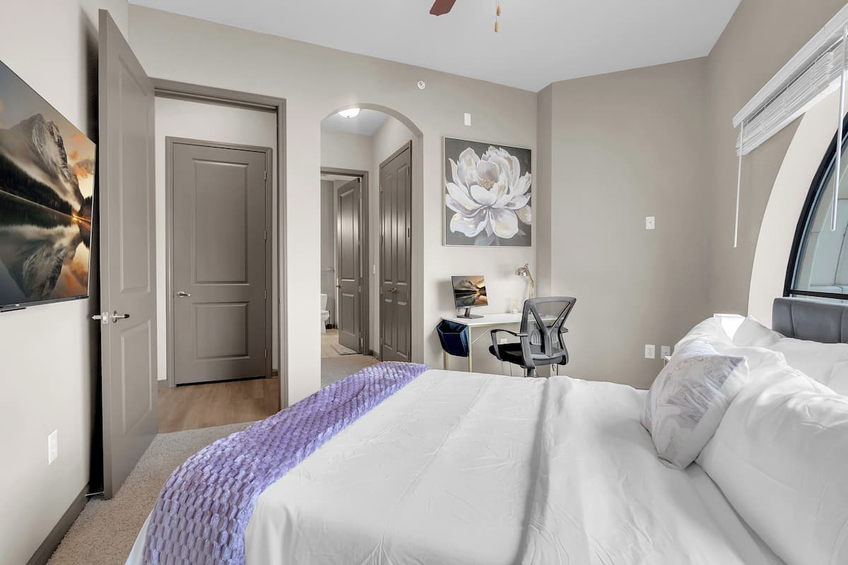 A bedroom with a bed, a desk, and a chair.