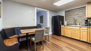 Una cocina compacta con una mesa de comedor de madera, sillas, un refrigerador negro y un salpicadero de piedra.