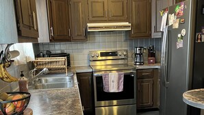 A modern kitchen with stainless steel appliances, wooden cabinets, and a tiled backsplash. - Pet friendly 3-bedroom. About a mile from downtown. Fenced-in backyard. (Hudson’)