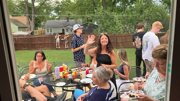 A group of people seated around a table outdoors with a view of a backyard and houses in the background. - Pet friendly 3-bedroom. About a mile from downtown. Fenced-in backyard. (Hudson’)