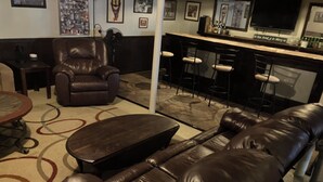 A living room with a leather sofa, a coffee table, a bar area with stools, and a television. - Pet friendly 3-bedroom. About a mile from downtown. Fenced-in backyard. (Hudson’)