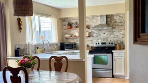 A dining area with a round table, chairs, and a hanging light fixture. - Delightful 3-bedroom Spanish inspired house in Richmond. The Rustic Villa. (Richmond)