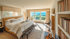 Un dormitorio con una cama grande, vistas al exterior y una estantería.