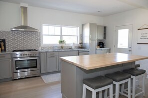 A modern kitchen with a central island, stainless steel appliances, and a large window.