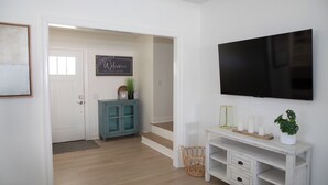 Un salon moderne avec un téléviseur à écran plat, un meuble turquoise et une console blanche.