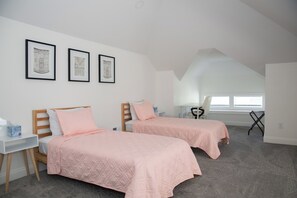 A bedroom with two beds, a desk, and a chair.