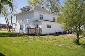 A two-story white house with a wooden deck and a small porch.