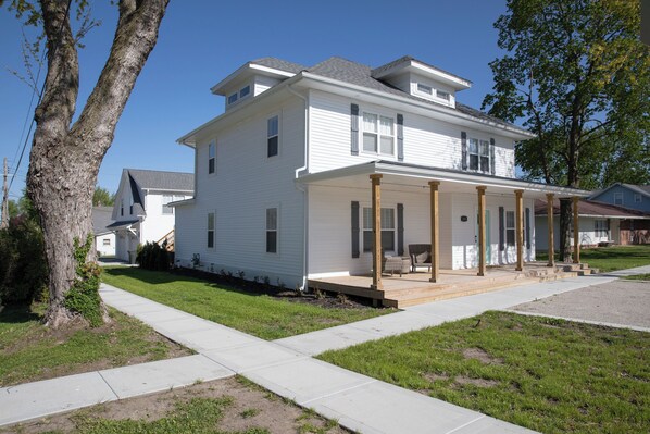 A two-story house with a covered porch and a small front yard.