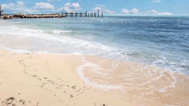 A beach with clear skies, calm water, and a wooden pier extending into the sea. - Waterfront Home with Dockage & 
 Steps to Cabana Club (Key Colony Beach)