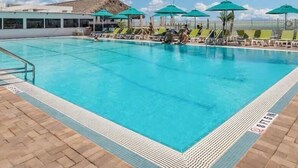 A swimming pool with lounge chairs and umbrellas, a clear sky, and a flag. - Waterfront Home with Dockage & 
 Steps to Cabana Club (Key Colony Beach)