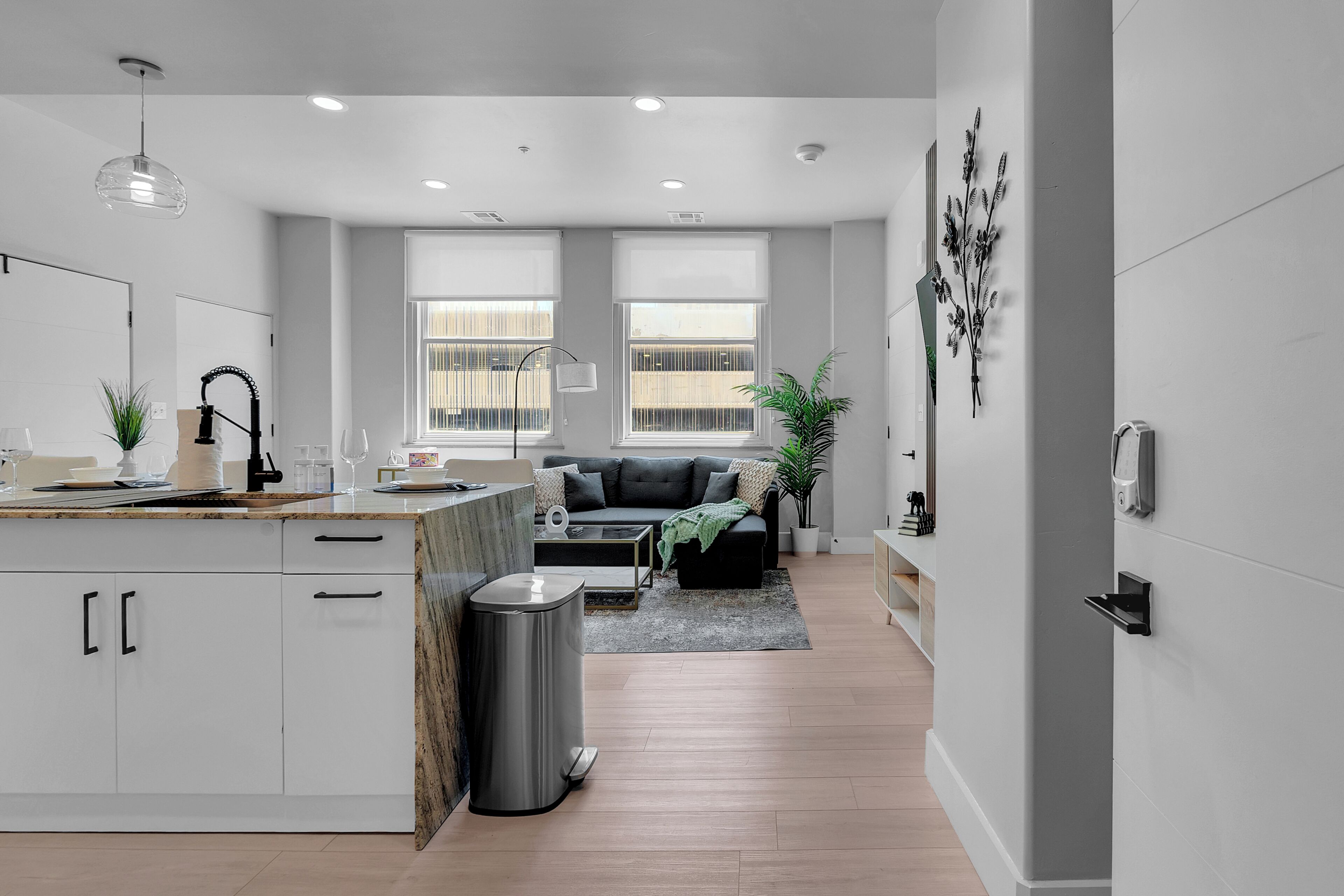 A modern kitchen with white cabinets, a granite countertop, and a stainless steel trash can.