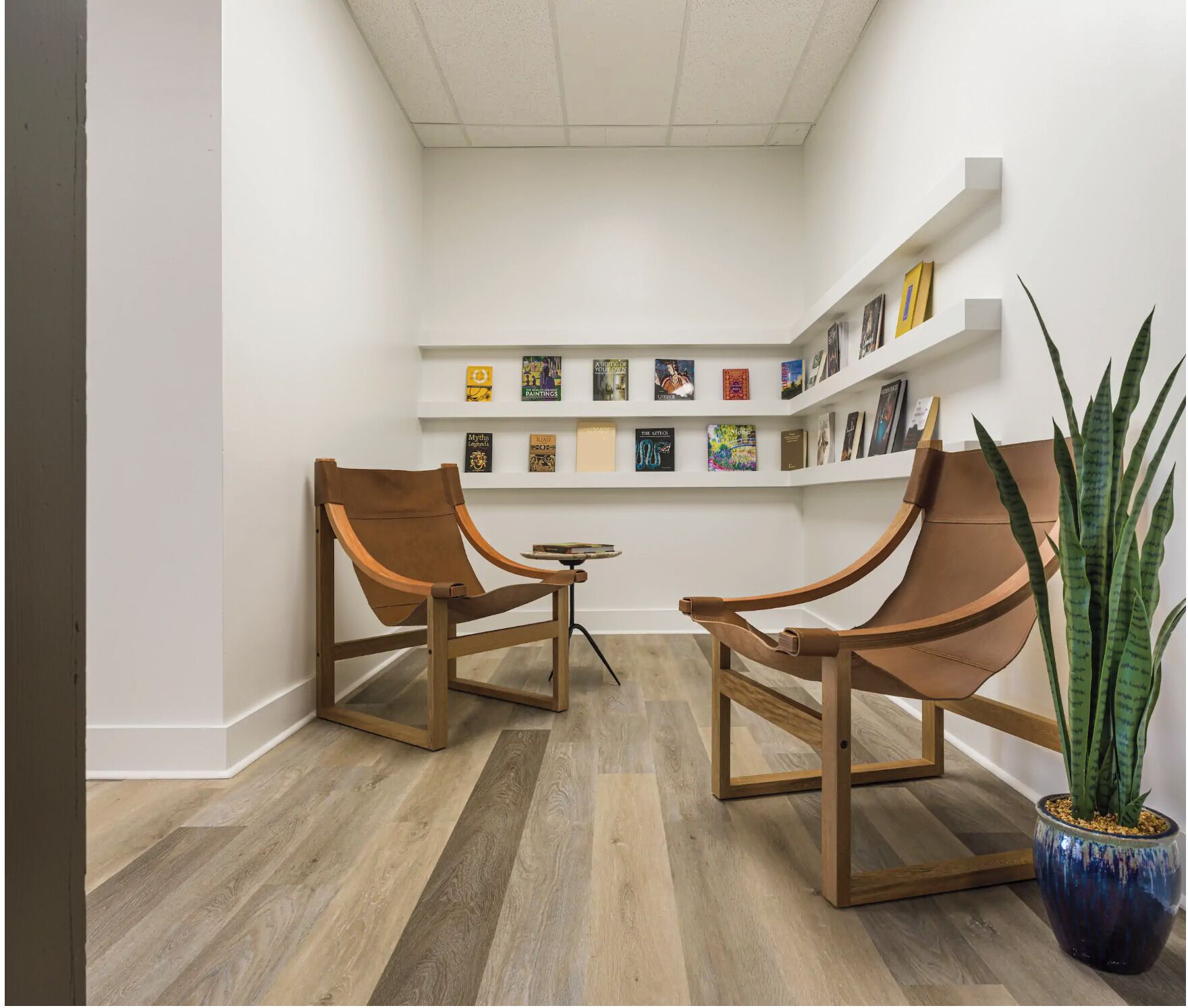Une pièce avec deux chaises en bois, une petite table et une plante en pot.