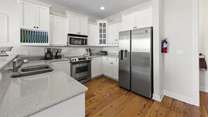 A modern kitchen with white cabinets, stainless steel appliances, and a wooden floor. - TOP FLORIDA's Villa Porpoise Point (Cape Coral)