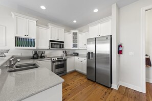A modern kitchen with white cabinets, stainless steel appliances, and a wooden floor. - TOP FLORIDA's Villa Porpoise Point (Cape Coral)