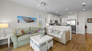 A living room with a sofa, a coffee table, a dining table, and a kitchen in the background. - TOP FLORIDA's Villa Porpoise Point (Cape Coral)
