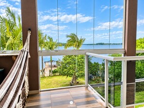 Un balcón con vista a un lago, palmeras y una zona ajardinada.