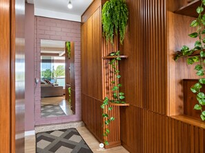 Un pasillo con pared de paneles de madera, un espejo y una planta colgante.