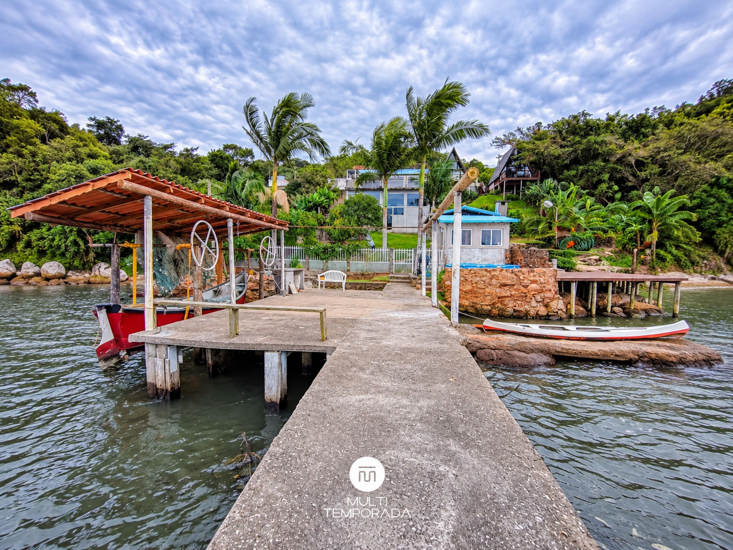 A dock extending into calm water with boats moored at the end.