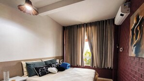 A hotel room with a bed, pillows, a bedside table, a lamp, a window with curtains, and an air conditioning unit. - Casa na Lagoa Imaruí-SC (Imaruí)