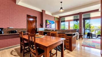 A modern kitchen with a dining area, large windows, and a view of the outdoors.