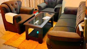 A living room with a sofa, two armchairs, a coffee table, and a ceiling fan. - 2-bedroom apartment in perfect Patna with cool AC (Patna)