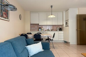 A compact living space with a kitchenette, a dining area, and a sofa.