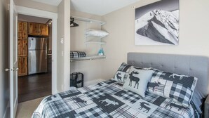 A bedroom with a bed, a mounted picture, a kitchenette, and a door leading to another room. - The Peachtree Paradise: Hot Tub, Free Shuttle (Crested Butte)
