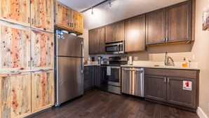 A modern kitchen with wooden cabinets, stainless steel appliances, and a fire extinguisher sign. - The Peachtree Paradise: Hot Tub, Free Shuttle (Crested Butte)